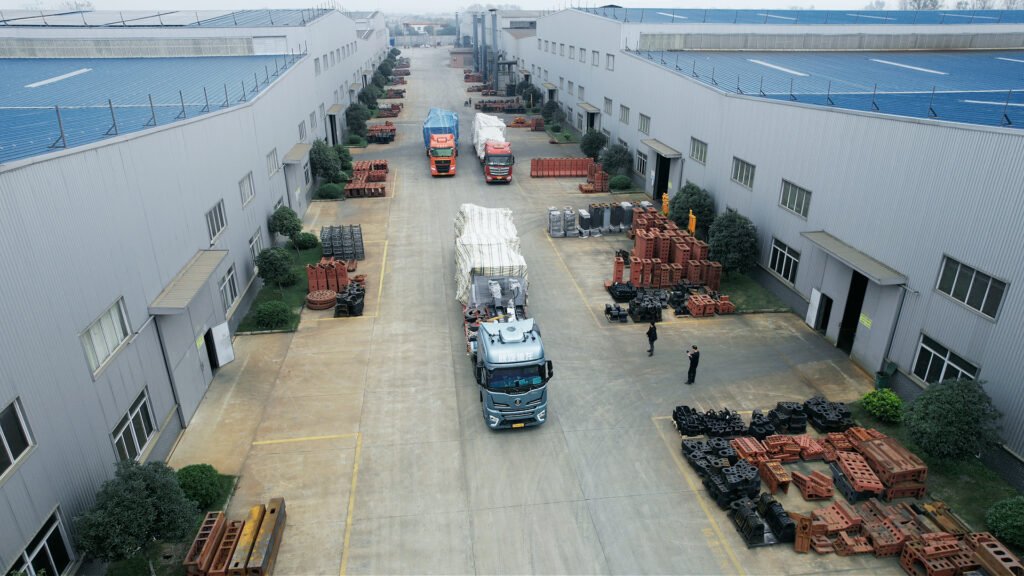 Tiezheng factory yard with production buildings, loading trucks, and organized machine components ready for shipment.